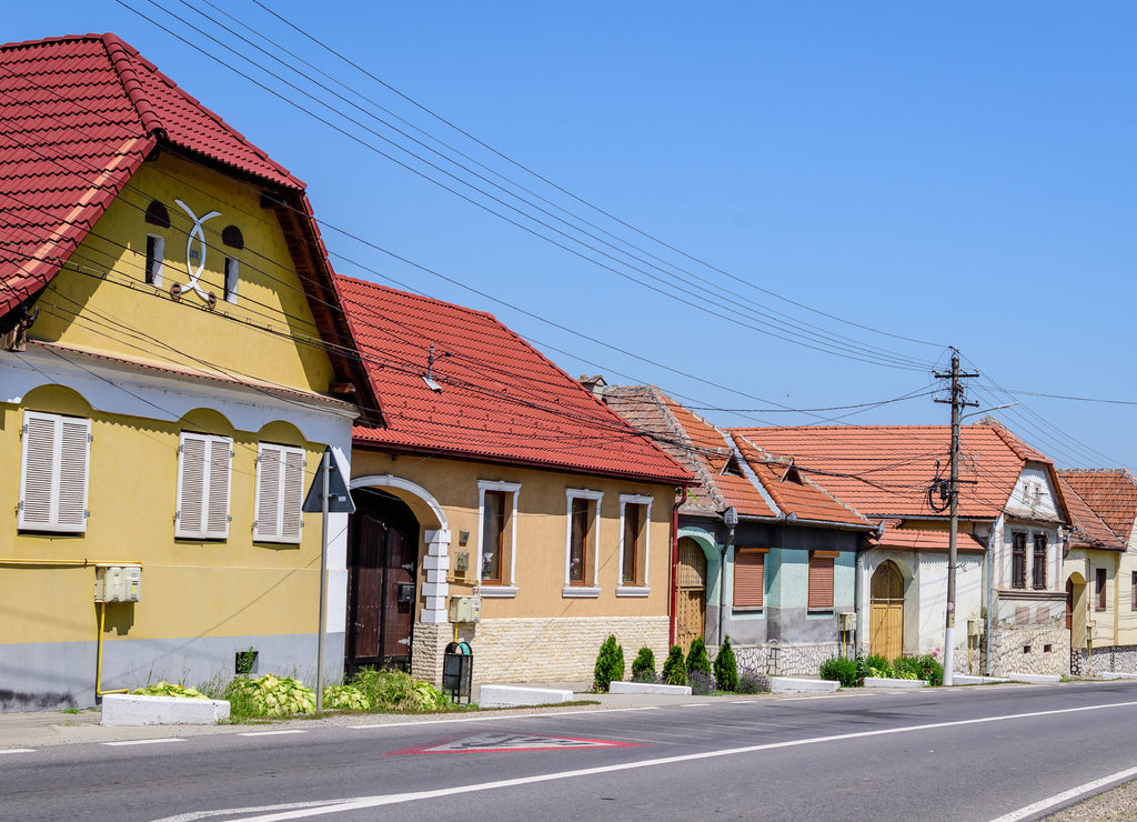 Colorful old houses near the fortitied church in Axente Sever village in Sibiu county, in Transylvania (Transilvania) region of Romania, in a sunny summer day