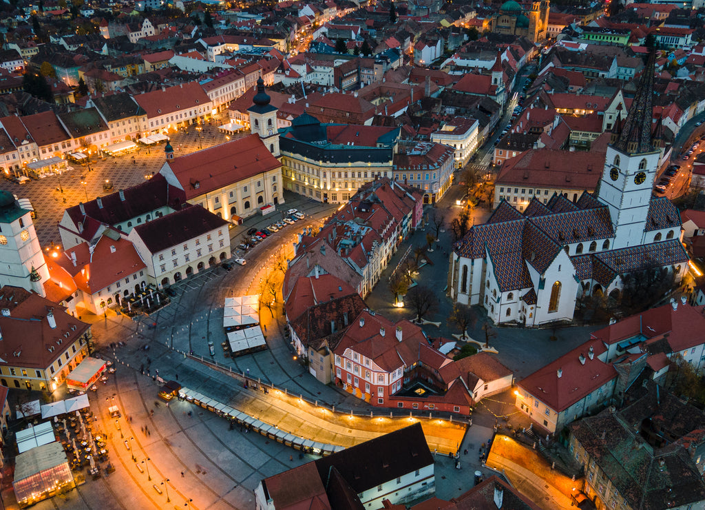 Birds eye view over historic city center of Sibiu, Romania at sunset. Drone photography from above containing the Evangelical Cathedral and Hued square, small square and the big square