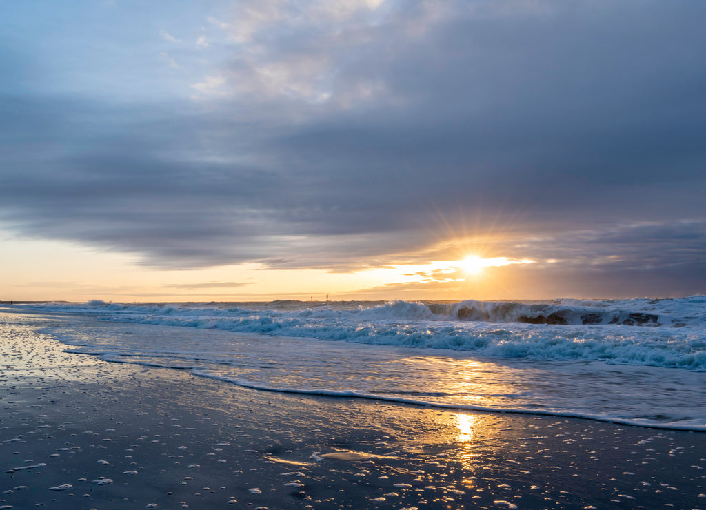 Beautiful sunrise over Long Beach Island, New Jersey featuring gorgeous waves and reflection on the foreground and dramatic sky on the background