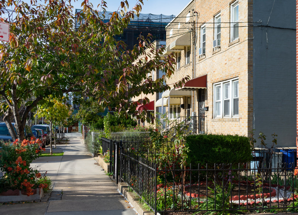 A Row of Old Fenced In Homes along a Sidewalk in Astoria Queens New York
