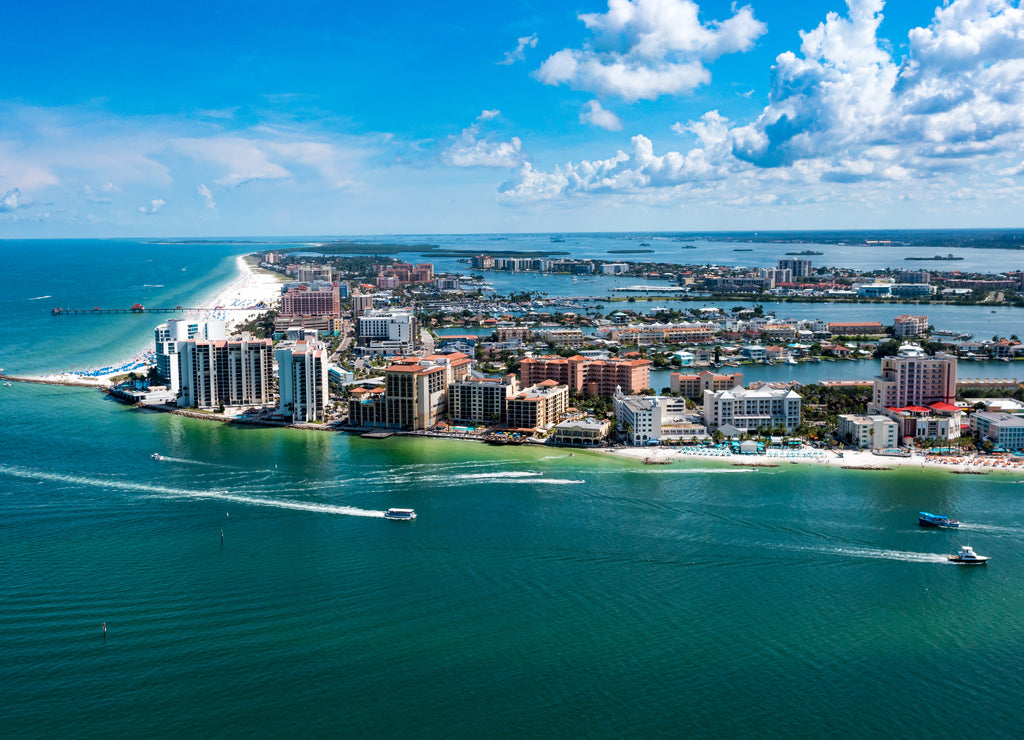 A view of Clearwater Beach Island in West Florida. White clouds on a deep blue background sky with boats going through the pass