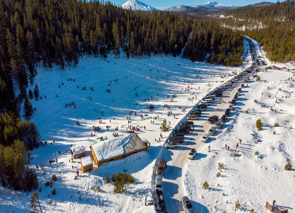 Aerial view at a sledding hill at Wanoga snow park, Central Oregon. People sledding down the hill enjoying sunny winter weather