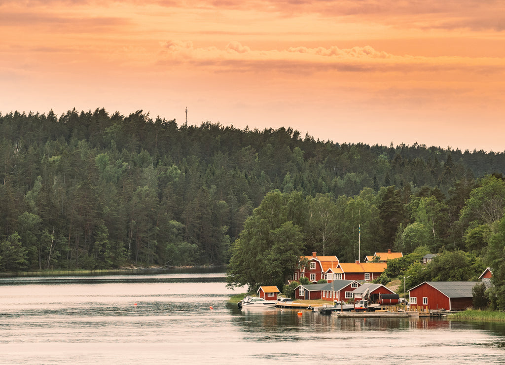 Sweden. Many Beautiful Red Swedish Wooden Log Cabins Houses On Rocky Island Coast. Lake Or River Landscape