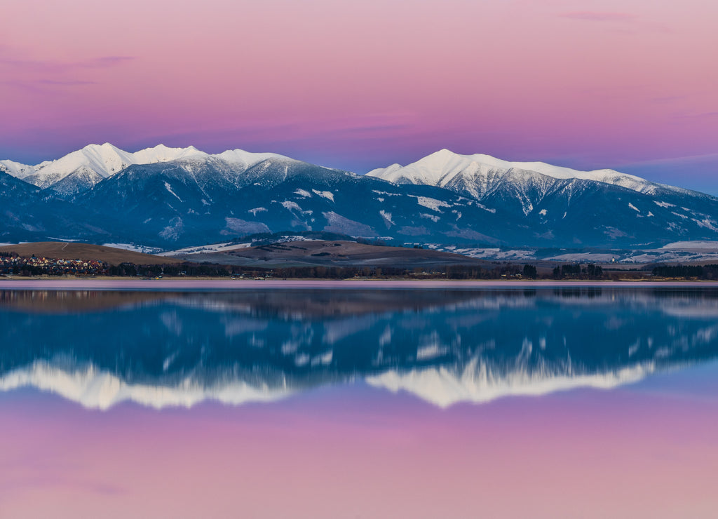 Winter landscape at sunset. Snow-capped mountains reflected in the lake. Liptovska Mara dam with the Western Tatras mountain in the background, Slovakia, Europe