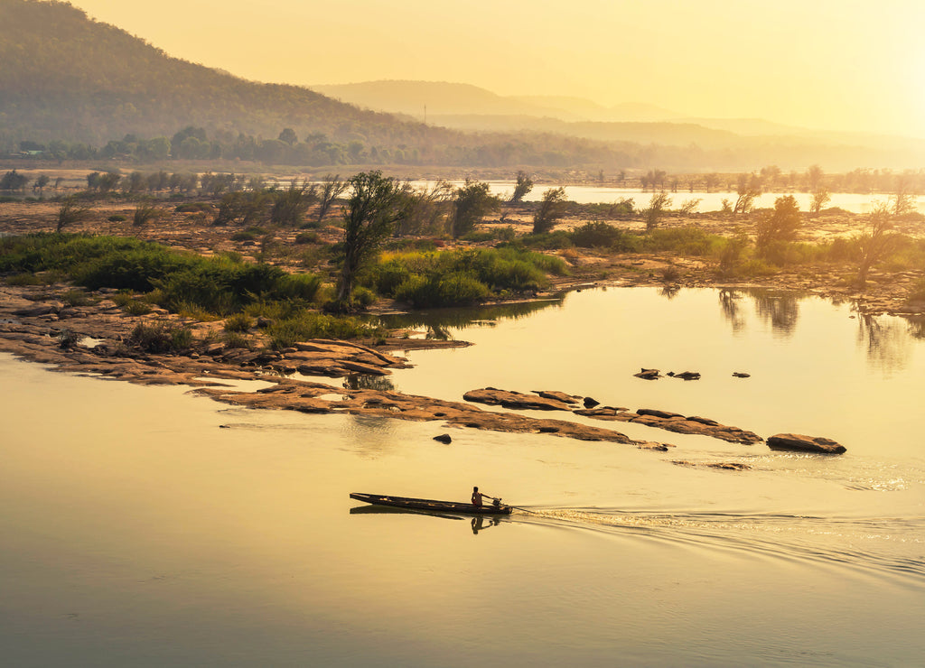 wooden fishing boat sailing in mekong river on sunrise at khongjiam district of thailand border of thailand and laos