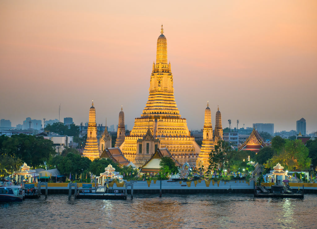Illuminated Temple of Dawn or Wat Arun and Thonburi west bank of Chao Phraya River at sunset. Bangkok, Thailand