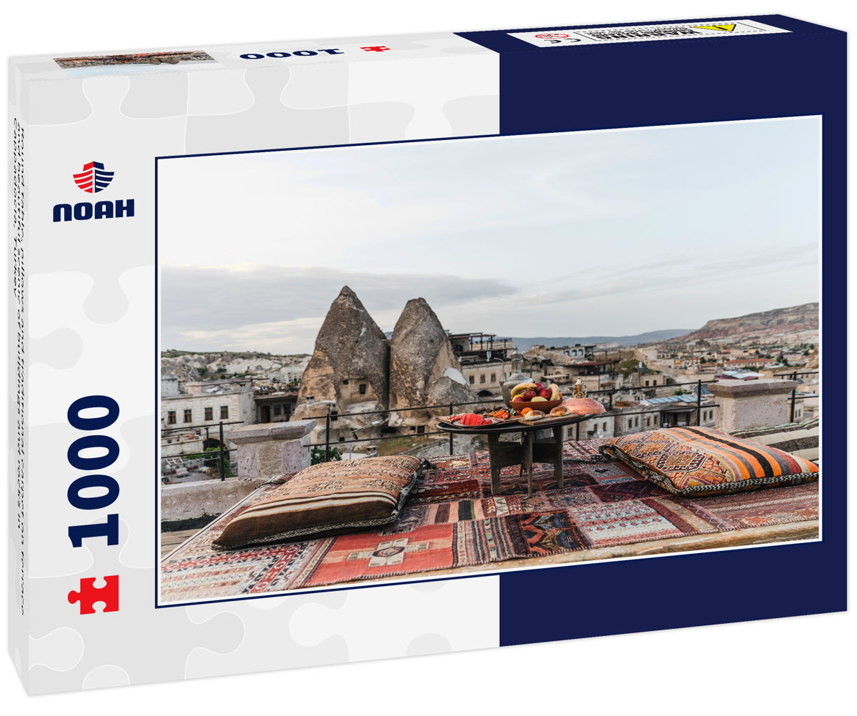 Round table, pillows and traditional carpet on terrace and beautiful scenic of buildings and rocks in Cappadocia, Turkey