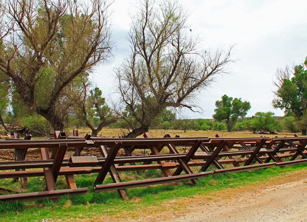 Dry river bed with a river border Fence beside a road near Nogales, Arizona separating the United States from Mexico