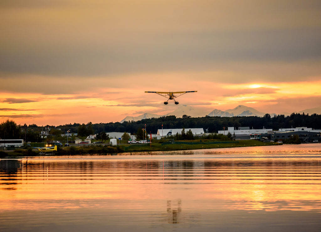 Sunset Over a Lake in Anchorage Alaska with a Float Airplane Taking off in the Distance