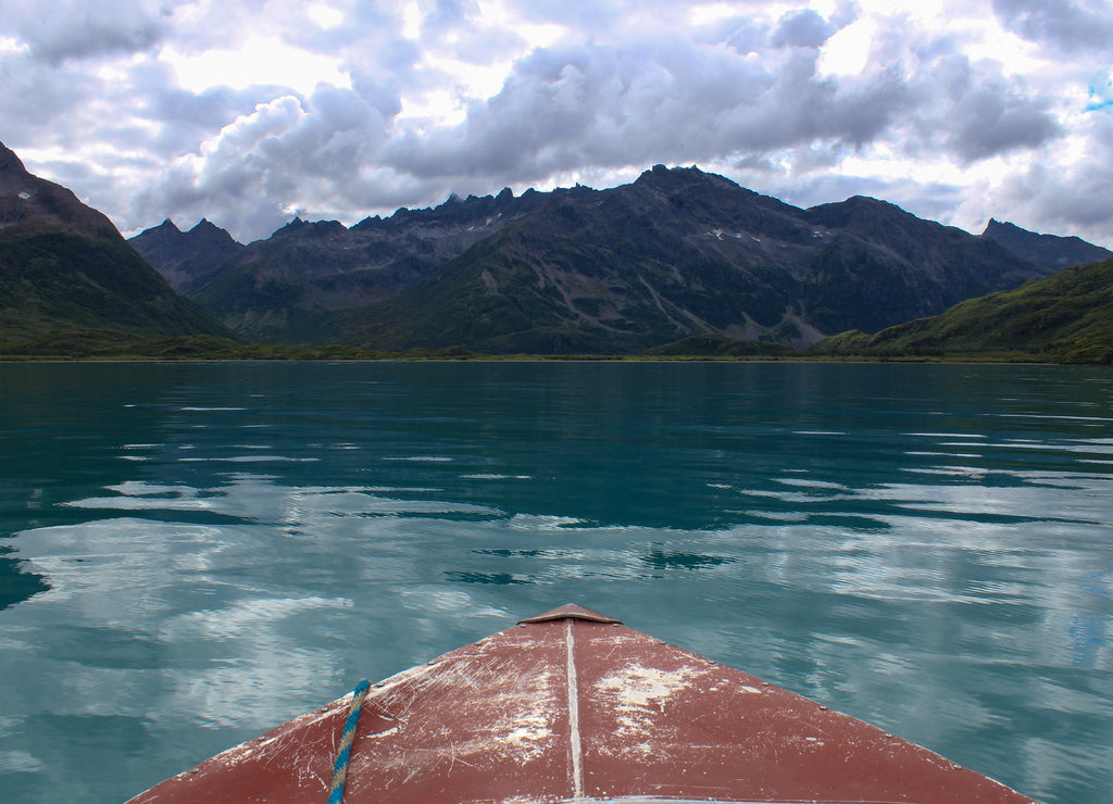 Front view from a red boat in blue lake water towards a mountain view in Mirror Lake in Bristol Bay area of Alaska