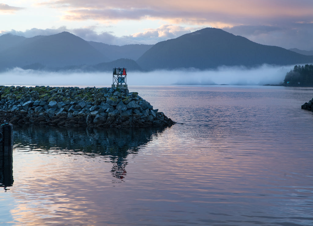 Sea smoke on sunrise of Sitka Alaska harbor, piers with docked boats clouds and pink sky reflecting on pacific ocean