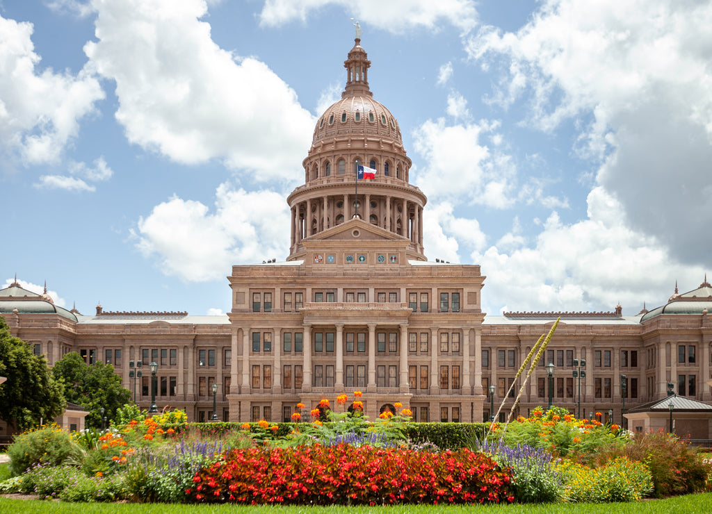 Texas State Capitol in Austin, Texas on a sunny summer day with colorful flowers in the front yard
