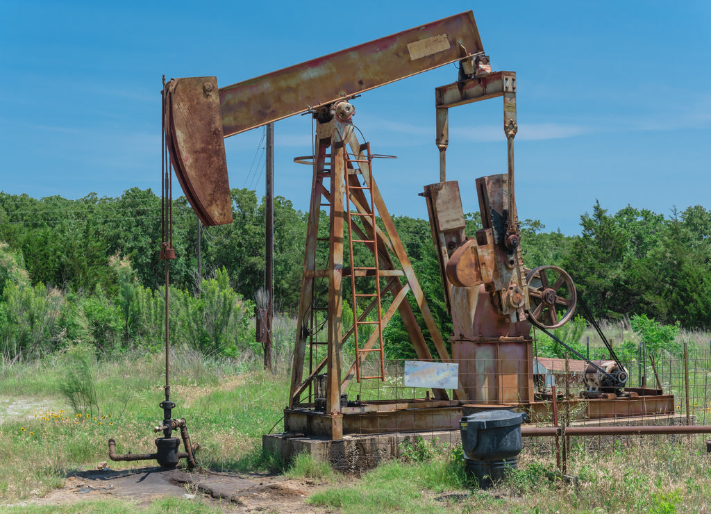 Close-up working pump jack fracking crude extraction machine. Pumping crude oil out of well to tank. Pumper, water emulsion at oil drilling site in Gainesville, Texas, US. Energy, Industrial background