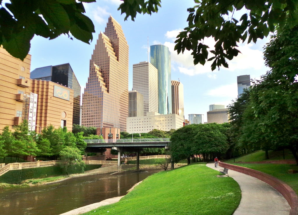 Bicyclist on Paved Bike Path in Buffalo Bayou Park, with the Skyline of Downtown Houston in the Background - Houston, Texas, USA