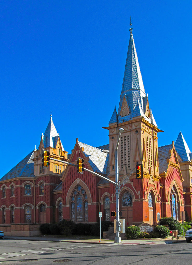 Beautiful church building in Greenville, Texas, USA. Bright red brick wall of house with stained-glass windows and decor detail against blue sky