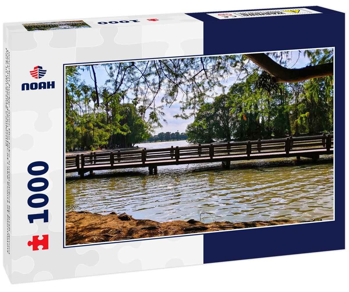 wooden bridge over the lake surrounded by lush green trees and deep green water at Lake Evans at Fairmount Park in Riverside California