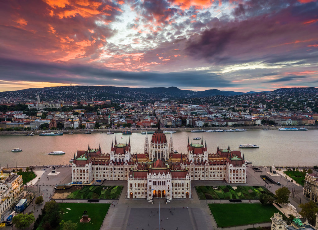 Budapest, Hungary - Aerial panoramic view of the Parliament of Hungary at sunset with beautiful dramatic purple clouds and sightseeing boats on River Danube