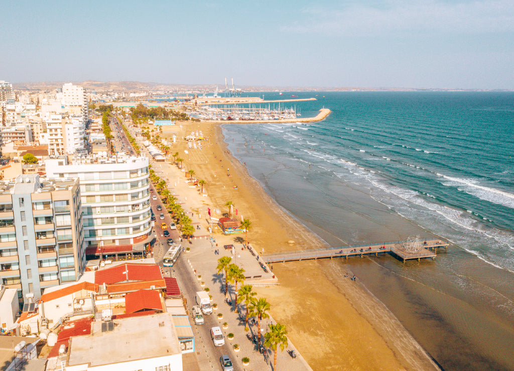 Aerial bird's eye view of Zygi fishing village port, Larnaca, Cyprus. The fish boats moored in the harbour with docked yachts and skyline of the town near Limassol from above. Larnaca lake
