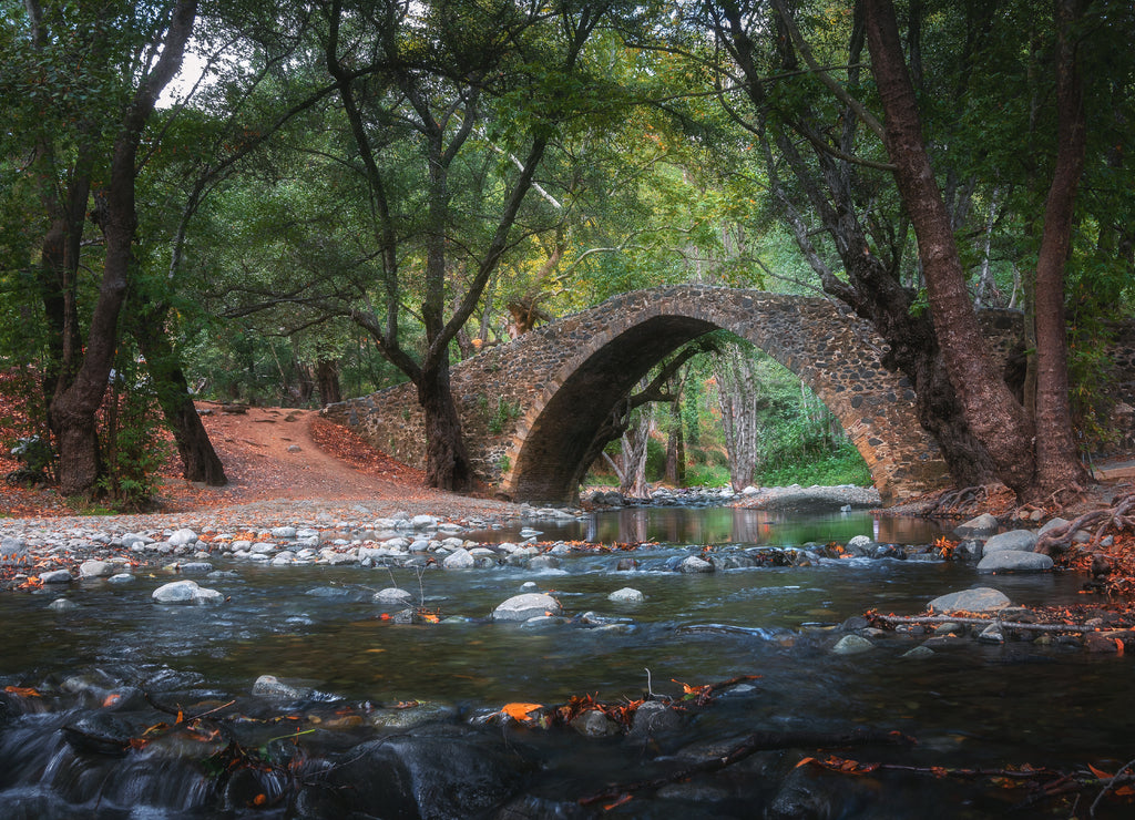 Venetian bridge in Cyprus in the Troodos mountains. Beautiful autumn landscape with river, trees and ancient bridge. Medieval architecture