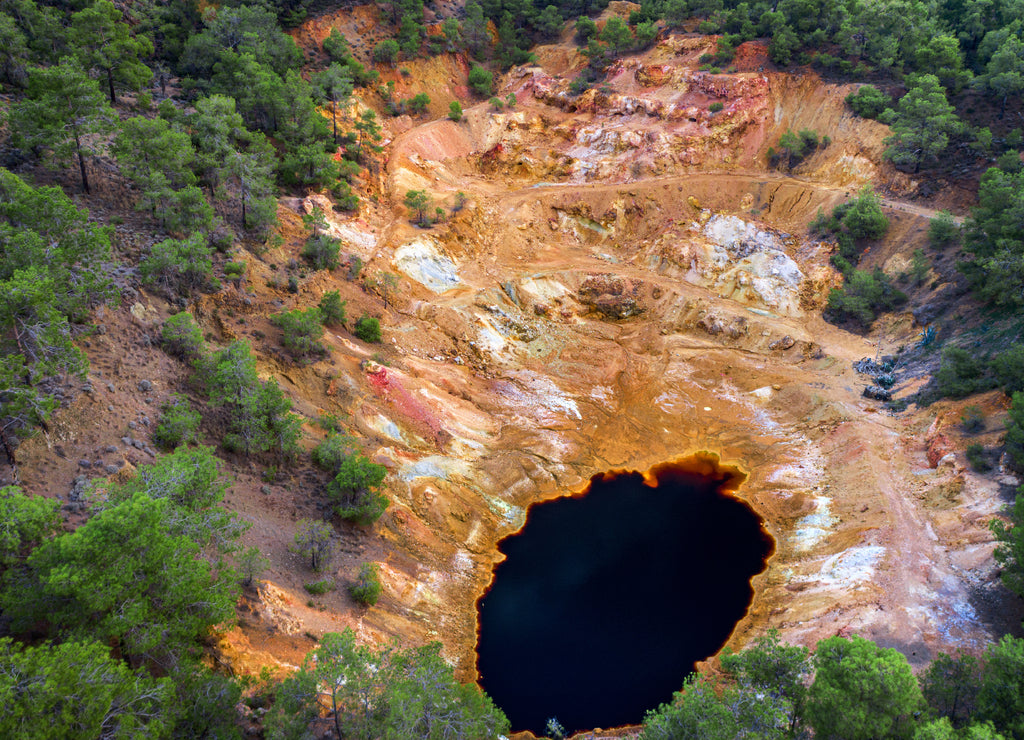 Abandoned open pit mine near Mathiatis, Cyprus. Aerial view on acidic red lake and colourful mine tailings left after pyrite ore extraction