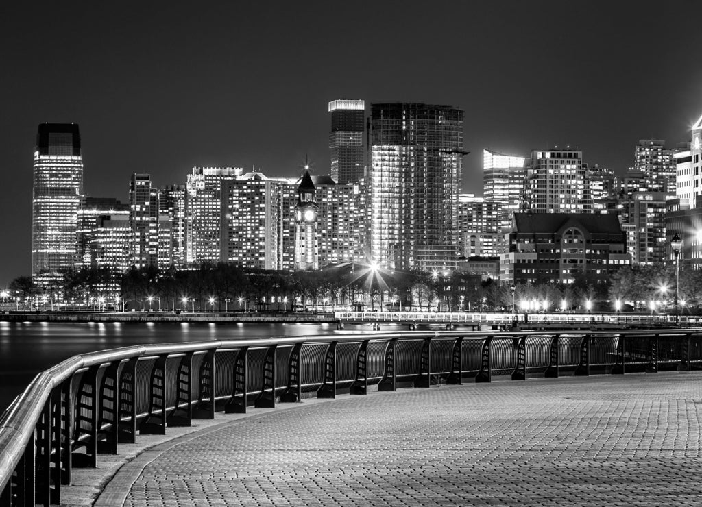 Jersey City skyline by night along Hudson river promenade, New Jersey in black white