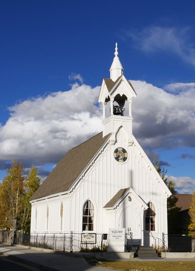 Wide portrait shot of a community Presbyterian church in Fairplay, Colorado, with beautiful clouds in the skies in the background