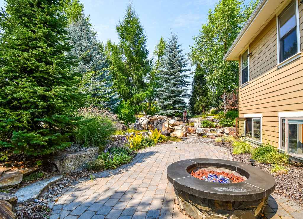 Lush landscaping including a fire pit and pond with waterfall in a luxury North Idaho, USA home