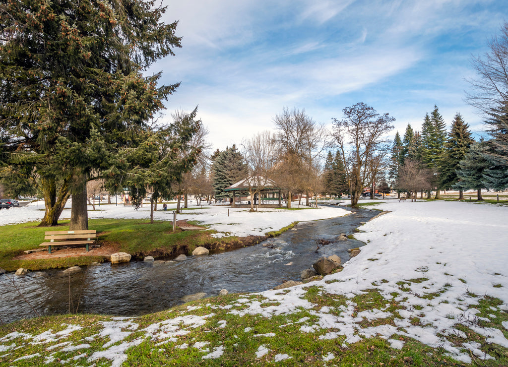 A small creek runs through the small public park with snow during winter at Rathdrum, Idaho USA