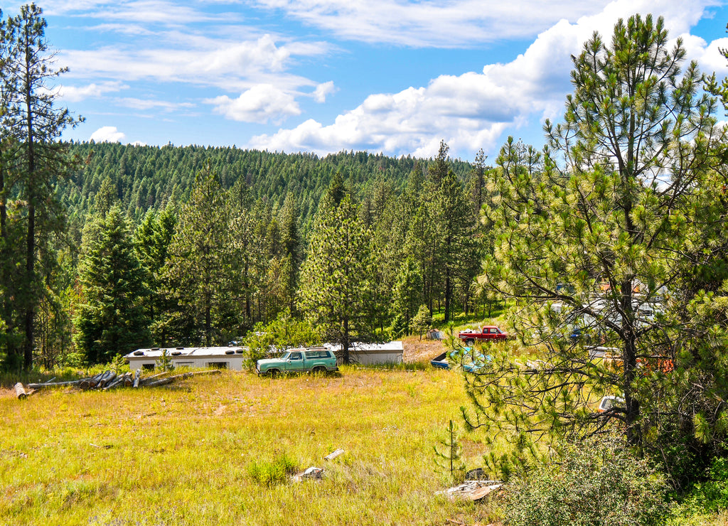 Cars, trucks and a mobile home are scattered throughout the hillside land in the North Idaho mountains