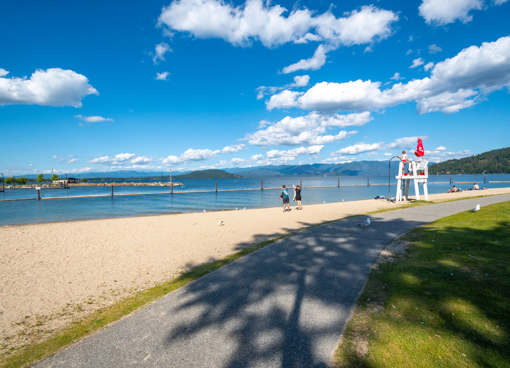 A lifeguard station with a female lifeguard on duty watching over the Sandpoint Idaho city beach and park along Lake Pend Oreille at summer