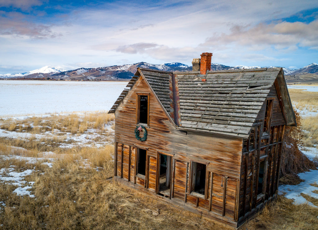 Abandoned farmhouse near Fairfield Idaho with snow in the mountains