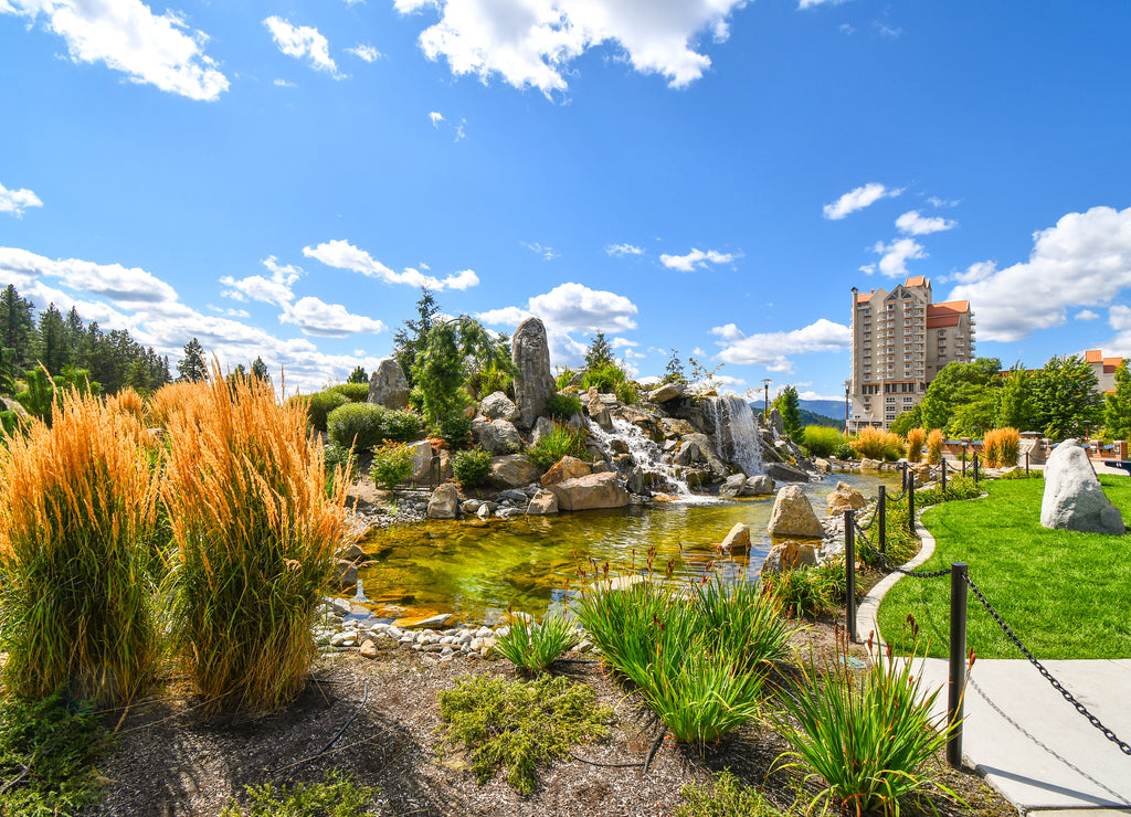 A large pond with waterfall inside the public McEuen Park near resorts and Tubbs Hill in the lakefront town of Coeur d'Alene, Idaho