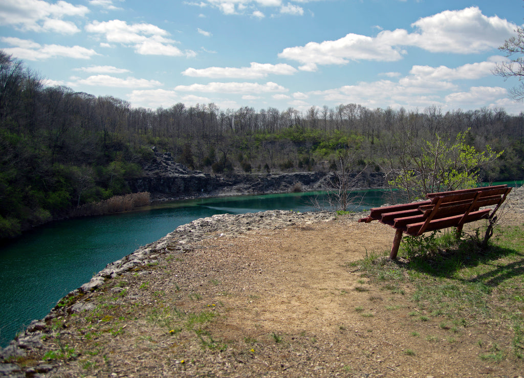 A metal bench sitting at the edge of an old limestone quarry at France Park in Cass county near Logansport Indiana