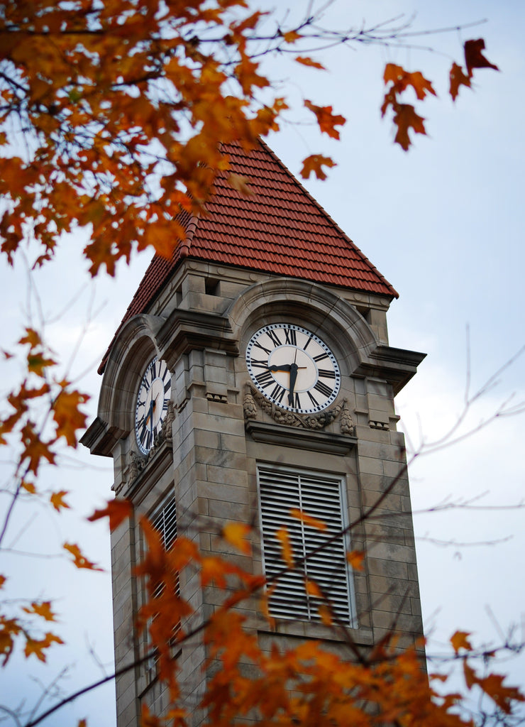 The clock tower of Indiana University in the fall in Bloomington, Indiana with colorful leaves