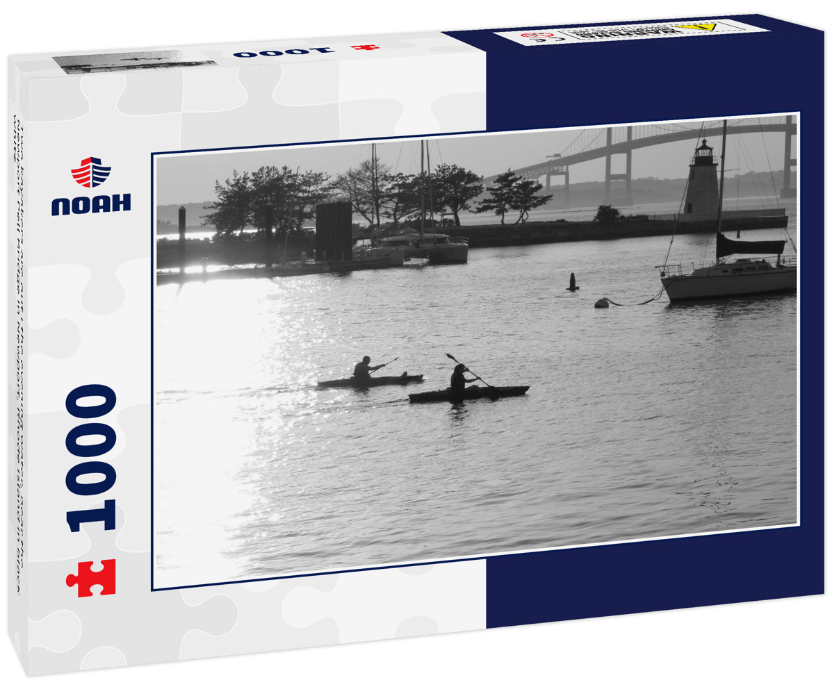 Two kayakers are out i the evening water, near the Newport Pell Bridge in Newport, Rhode Island in black white