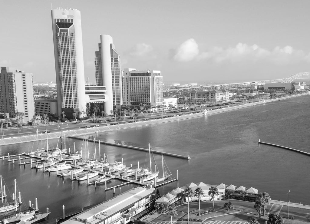 Panorama aerial view Bayfront area of Corpus Christi with skylines and marina piers row of boat, sailboat and yacht at sunrise. City harbor bridge far right in distance. A Texas city on Gulf of Mexico in black white