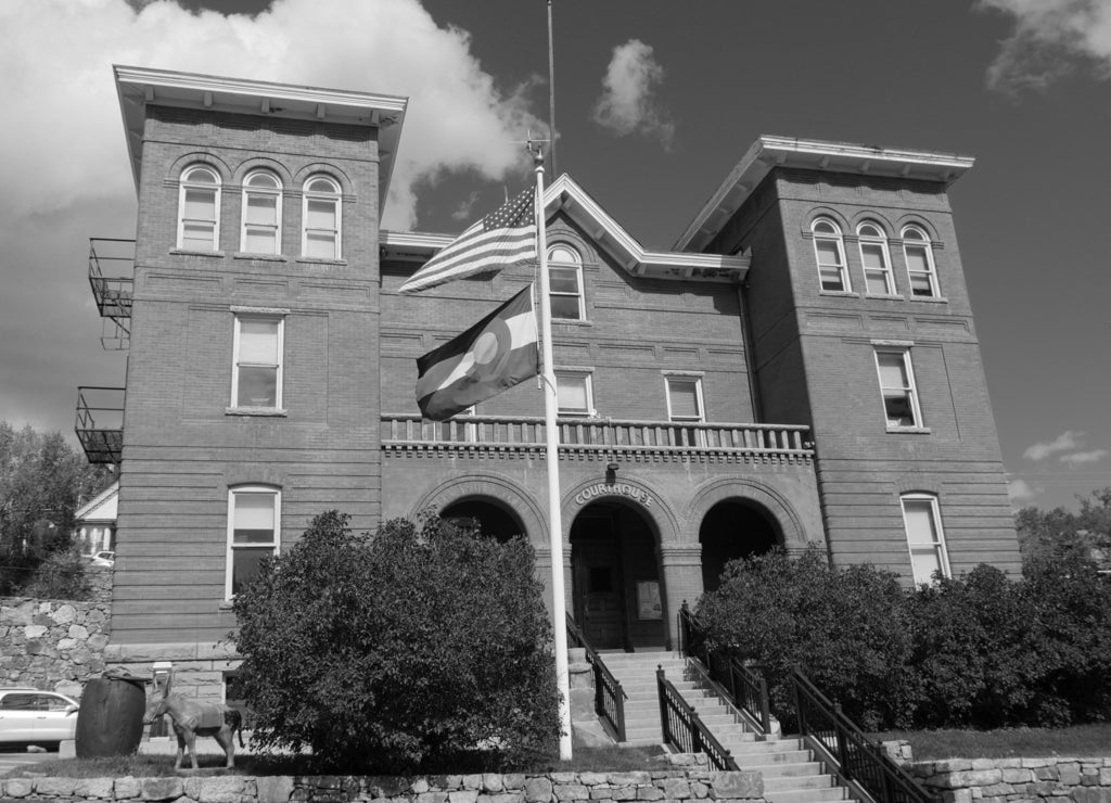 Front view of the Gilpin County Courthouse at Central City in Colorado, with the American and state flags in front in black white