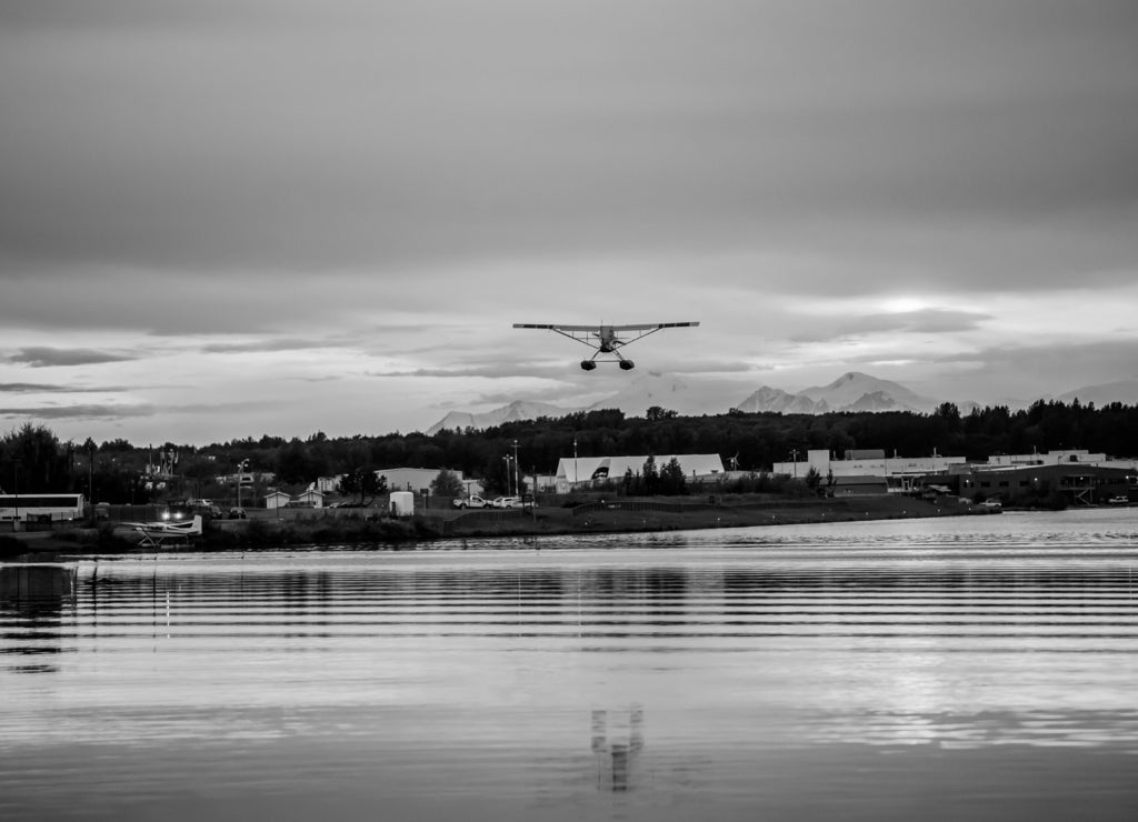 Sunset Over a Lake in Anchorage Alaska with a Float Airplane Taking off in the Distance in black white