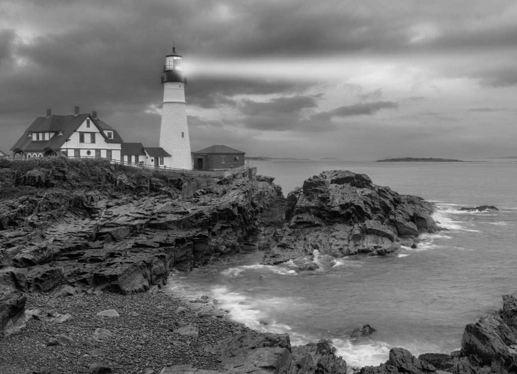 Lighthouse beam light in stormy clouds. Portland Head Light, Maine, USA in black white