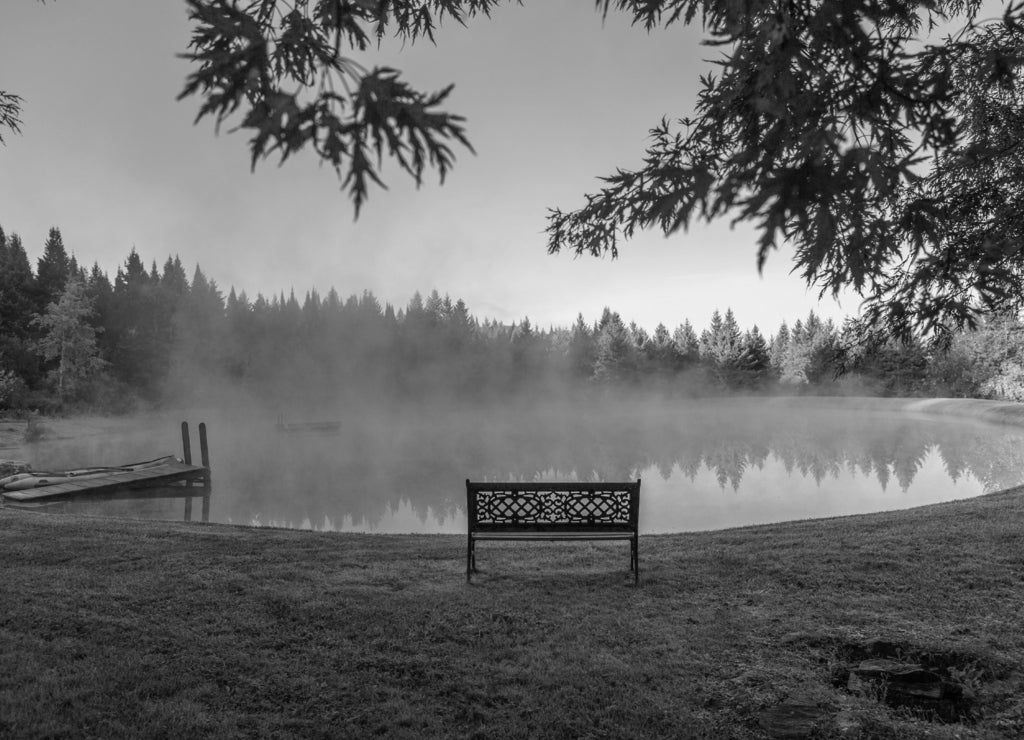 A decorative bench in front of a foggy pond, Stowe Vermont, USA in black white