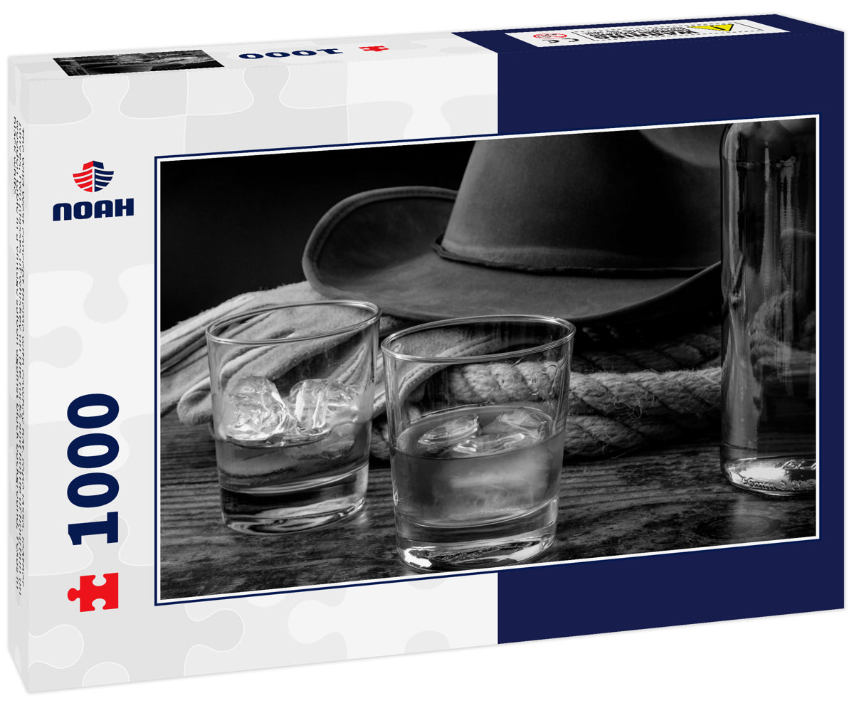 The Wild West concept theme with cowboy hat, rope lasso, leather gloves, two glasses of whiskey on the rocks and bottle of bourbon on wooden table in a vintage saloon against black background, Texas in black white