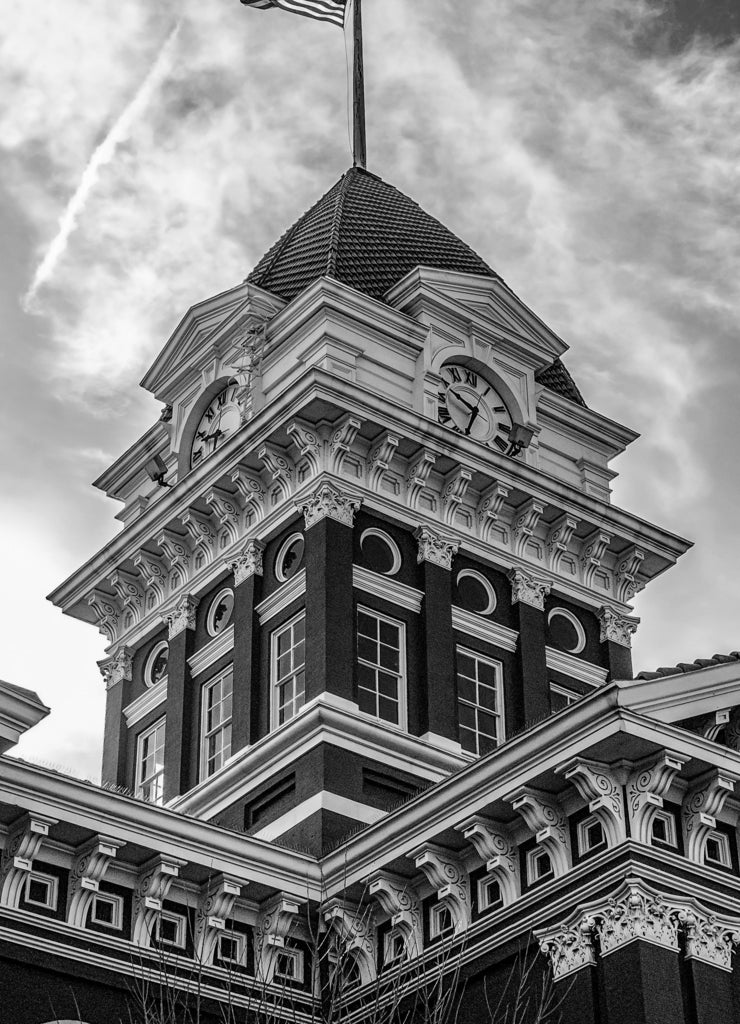Old Indiana courthouse clock tower with American flag on pole in black white