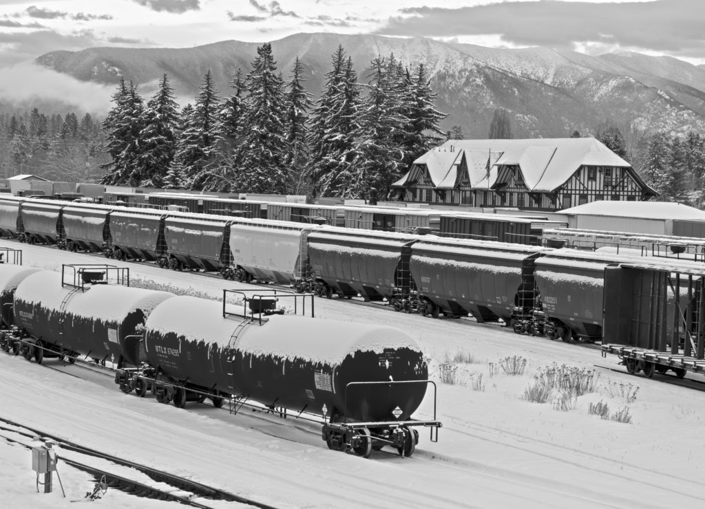 Rail yard in winter with trains, depot, and mountains in background, whitefish, Montana in black white