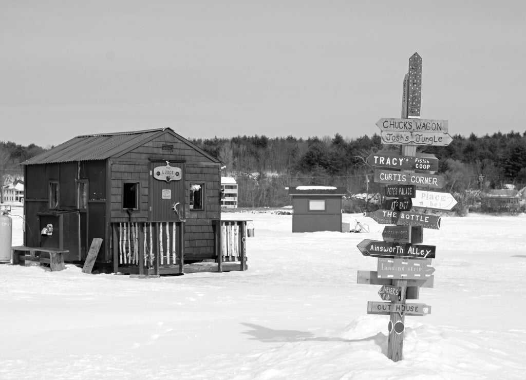 Signs point the way to a multitude of ice fishing shacks on Lake Winnipesaukee, New Hampshire in black white