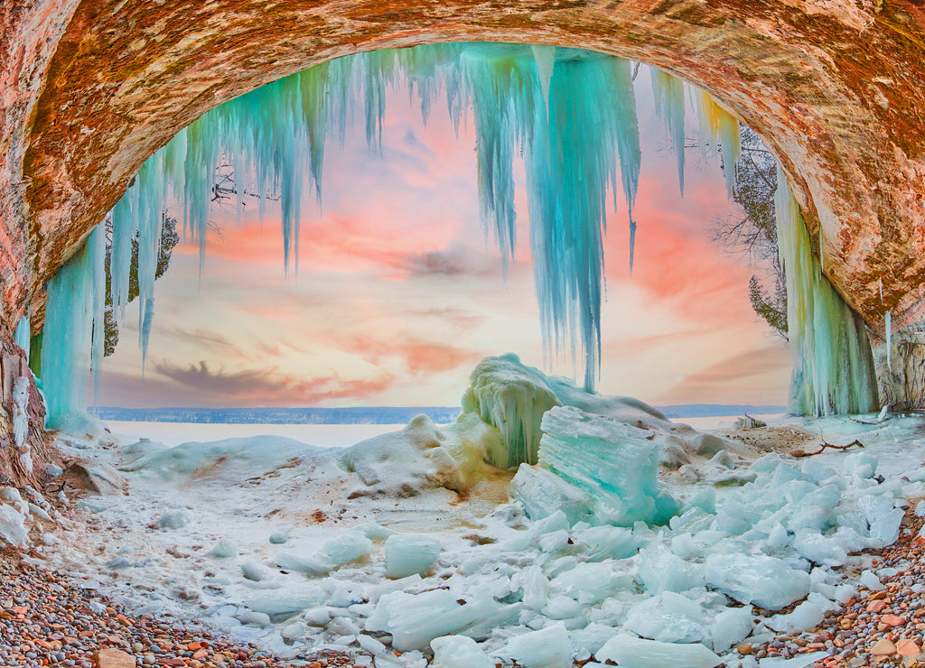 Ice cave on Lake Michigan during sunrise with large blue icicles