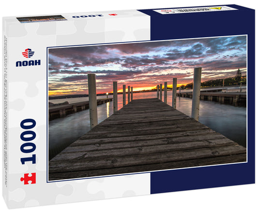 Wooden Dock On Sunrise Lake. Summer sunrise over the waters of Grand Traverse Bay in Traverse City, Michigan. Shot with long wooden dock in foreground sunrise over water at horizon