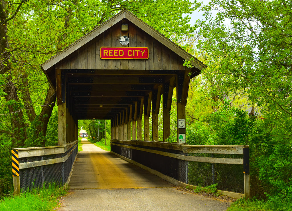 Covered wooden foot bridge over small peaceful creek in Reed City, Michigan