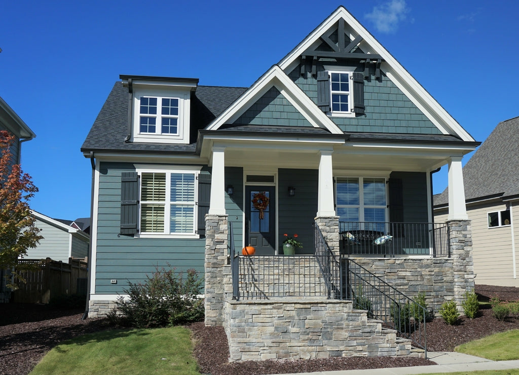 Exterior view of a two-story suburban home with a stone porch in autumn. Built in 2017 in North Carolina
