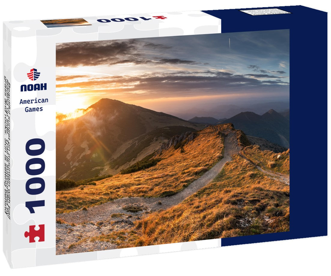 Noah Jigsaw Puzzle Beautiful sunset on mountain with trail leading up side. Trail is surrounded by grass and rocks. Sun is setting behind mountain, casting warm glow on 1000 pieces