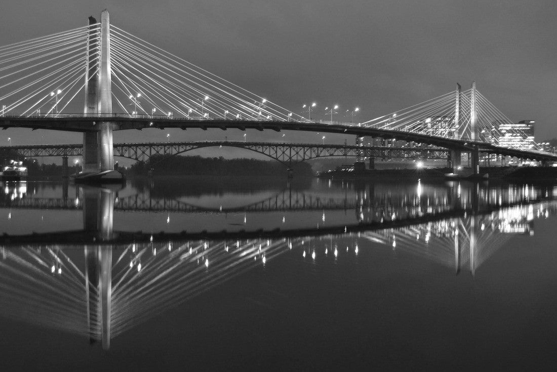The Tillikum Bridge crosses the Willamette River in Portland, Oregon. The lights from the city's modern structures are reflected in the calm waters 2000pc PuzzleBlack and White